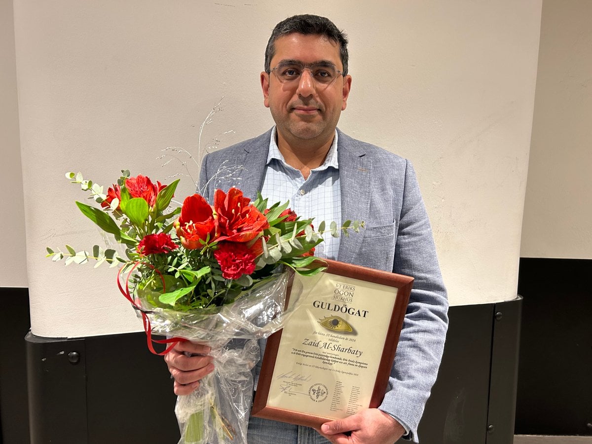 En man håller i en blombukett och ett diplom.