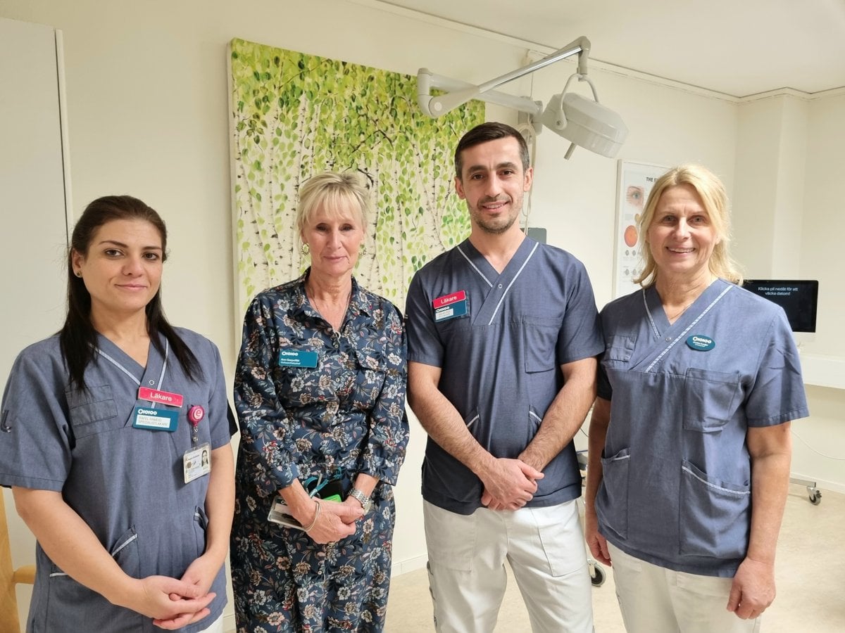 Fyra personer står bredvid varandra. Tre personer i sjukhuskläder och en person i blommig klänning.