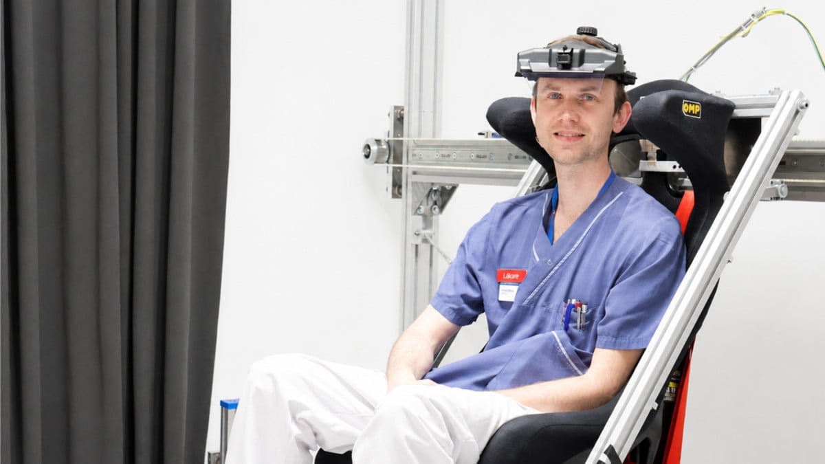 En läkare sitter i en mekanisk släde i forskningslaboratoriet. Han är iklädd sjukhuskläder och har ett eye-tracking verktyg på huvudet.