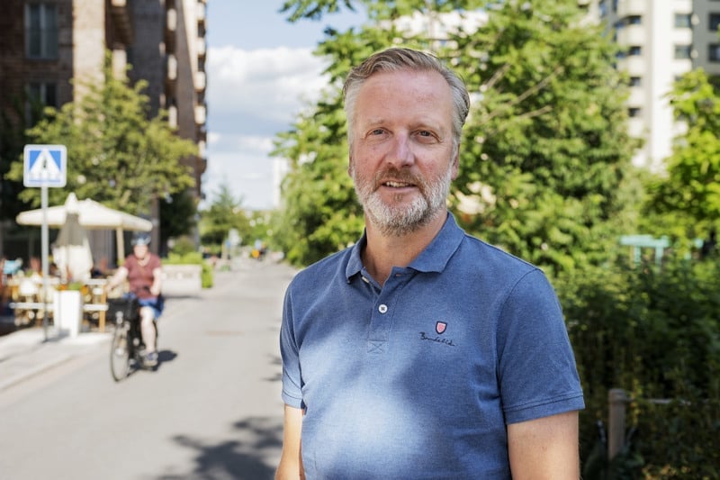 En man i blå skjorta står vid sidan av en väg.