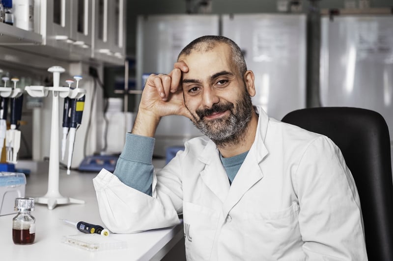 En man i labbrock sitter vid ett skrivbord.