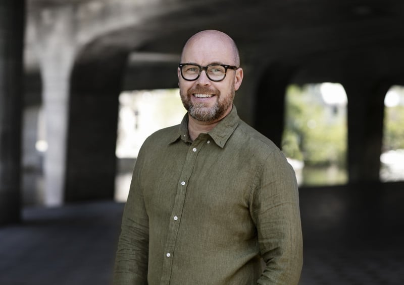 En man med glasögon står i en tunnel.