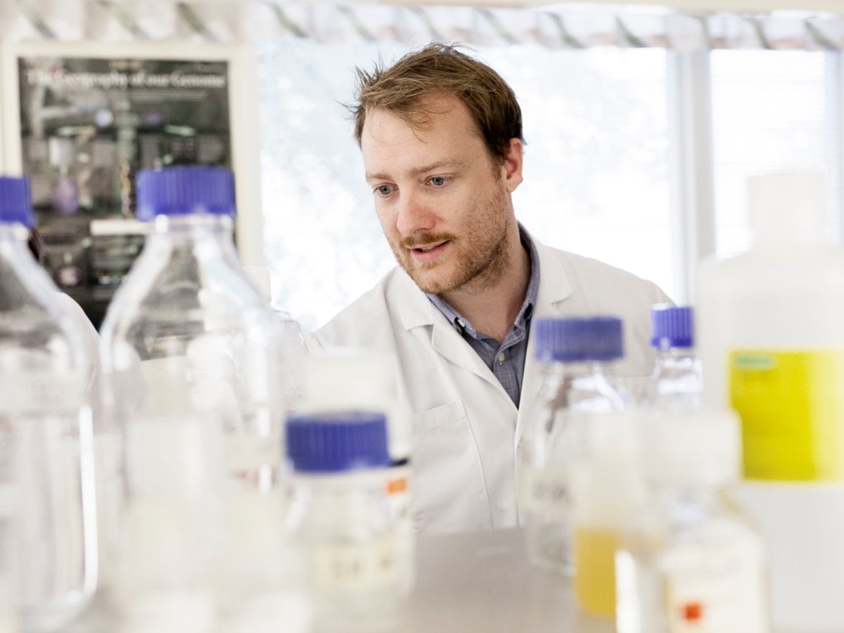 En man i labbrock står i ett laboratorium.