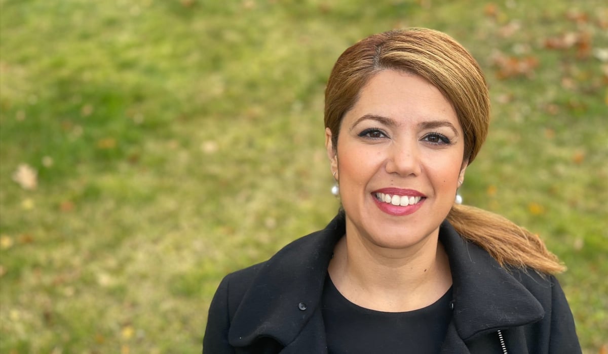 En leende kvinna står på en gräsmatta.