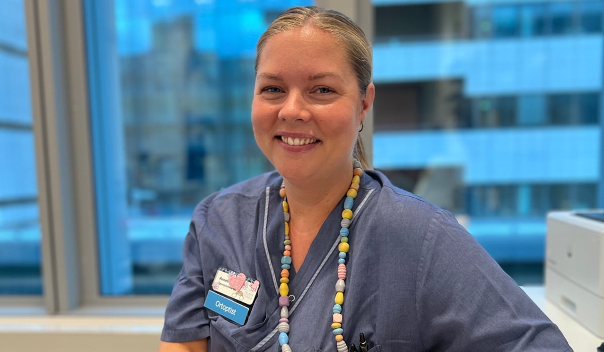 En kvinna i sjukhuskläder sitter vid ett skrivbord.