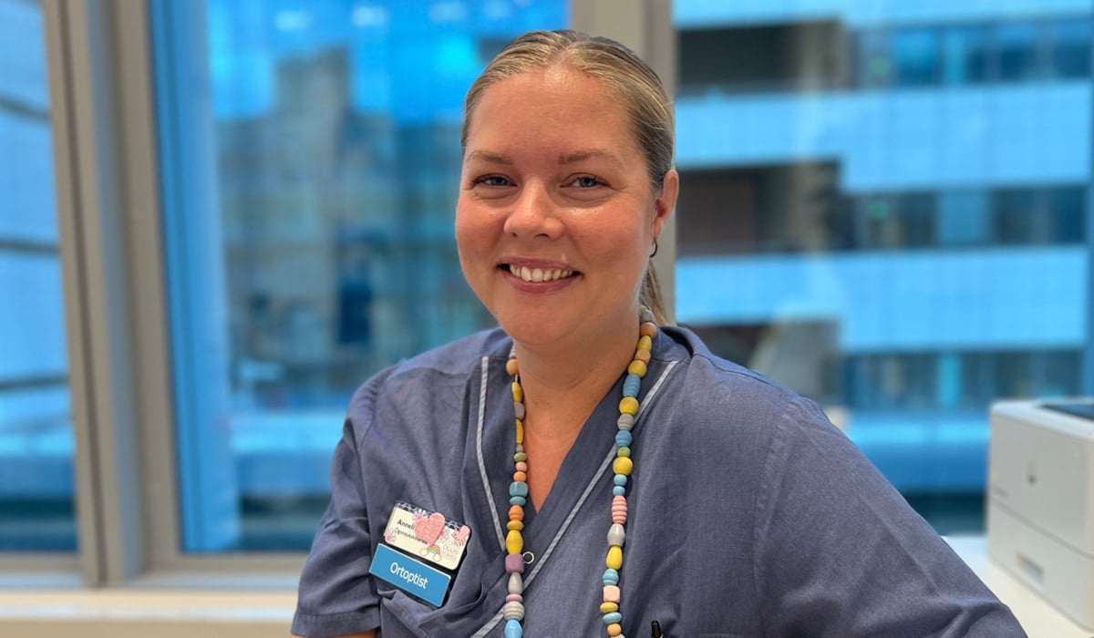 En kvinna i sjukhuskläder sitter vid ett skrivbord.