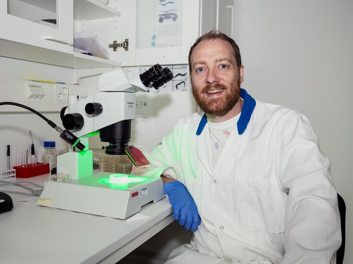 En man i labbrock och blå handskar.