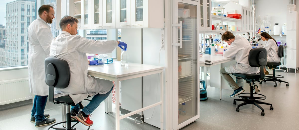 Fyra forskare med labbrockar som arbetar i ett laboratorium.