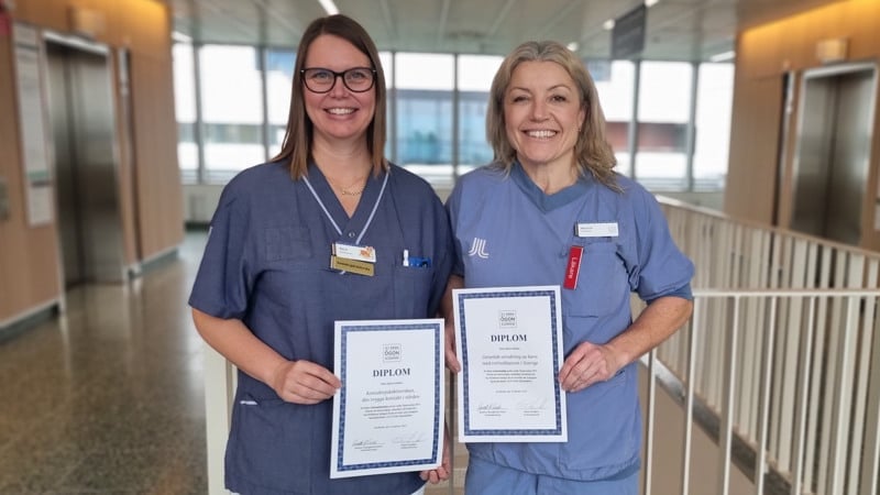 Marie Hellborg och Maria Fili står bredvid varandra med diplom för bästa postrar under Ögonveckan 2025 i sina händer.