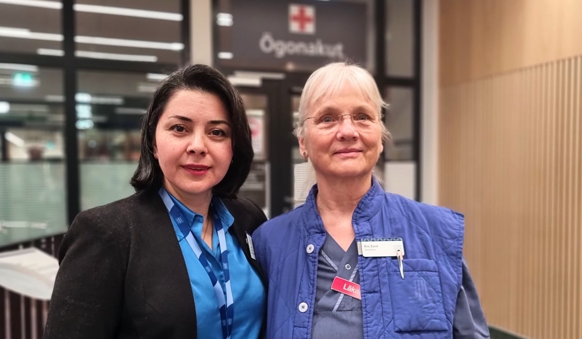 Två kvinnor som står bredvid varandra. I bakgrunden syns en skylt med texten Ögonakut.