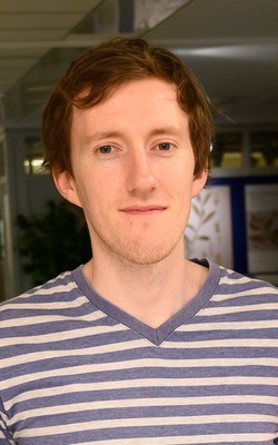 A man with dark hair and blue/white striped sweater.