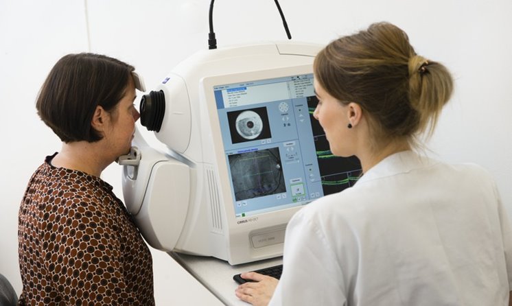 En kvinna sitter framför en maskin som tar bilder av hennes ögon inuti.