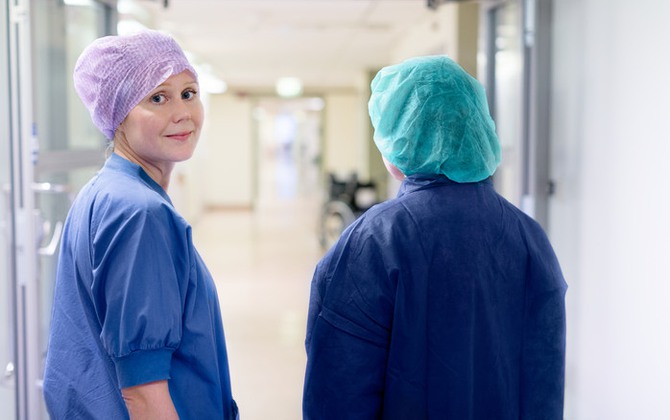 Sjuksköterska går med patient i korridor på operation